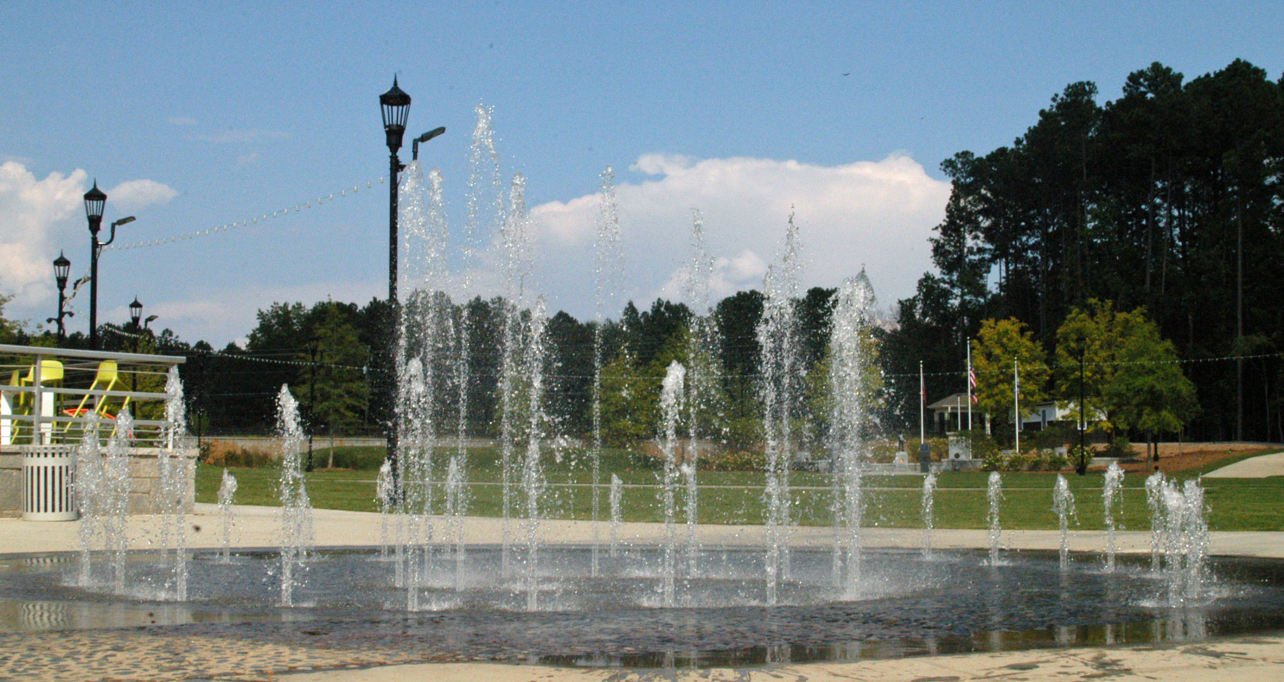 Interactive dry deck splash pad fountain at Peachtree Corners Town Center featuring water jets shooting up in a spiral pattern.